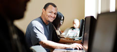 a and t student smiles for the camera while working on a laptop