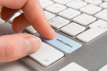 finger typing a keyboard key that says education