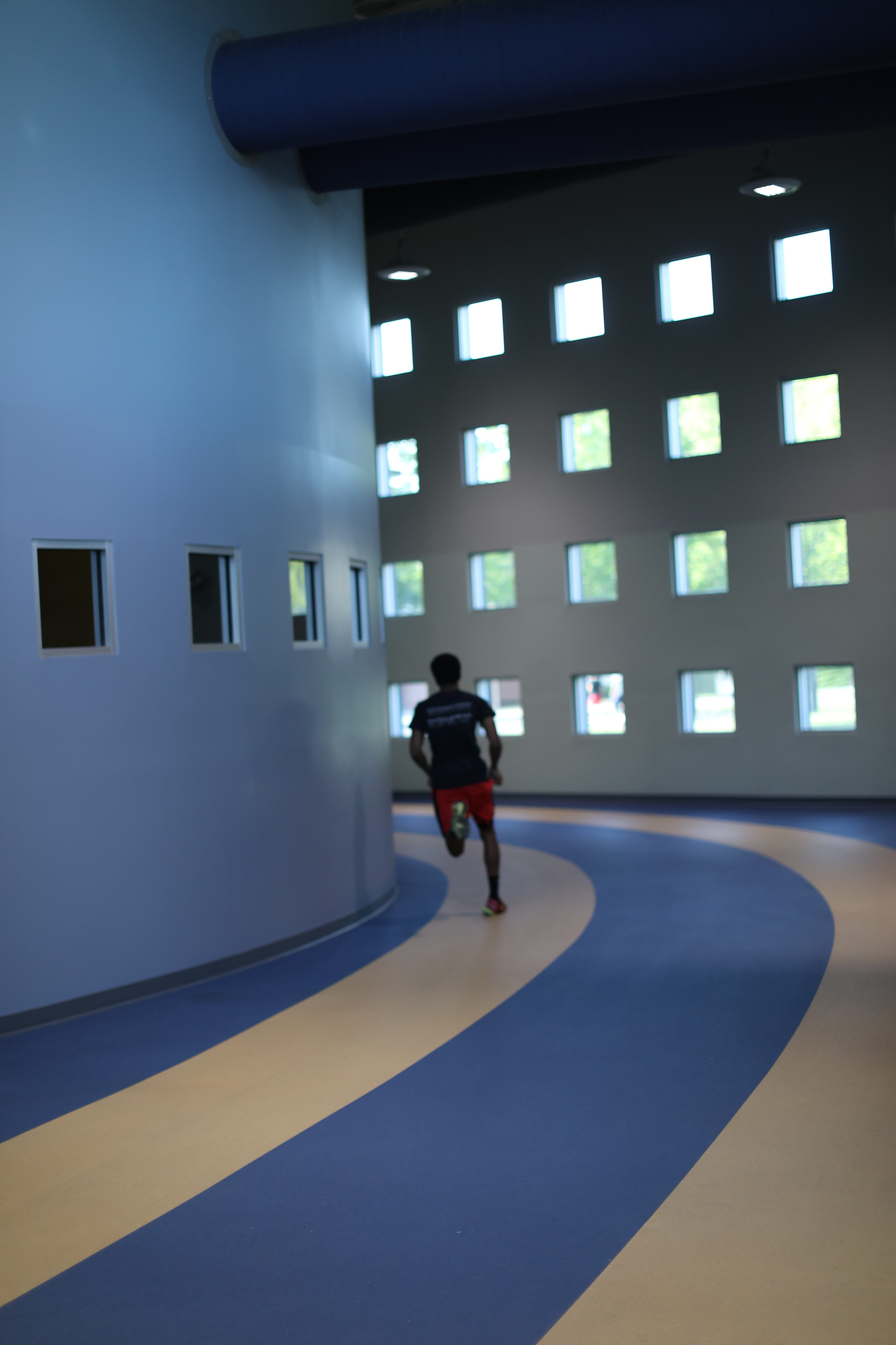  an a and t student runs on an indoor track - Campus Recreational Center