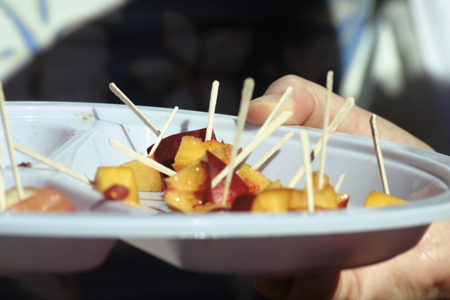 A plate of chopped fruit with tooth picks inserted in the slices for patrons to sample.