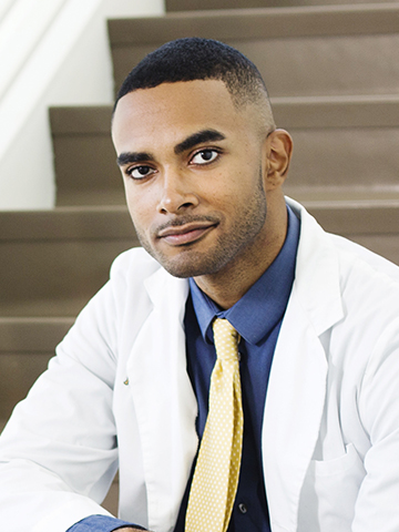 male student in white lab coat sitting on steps