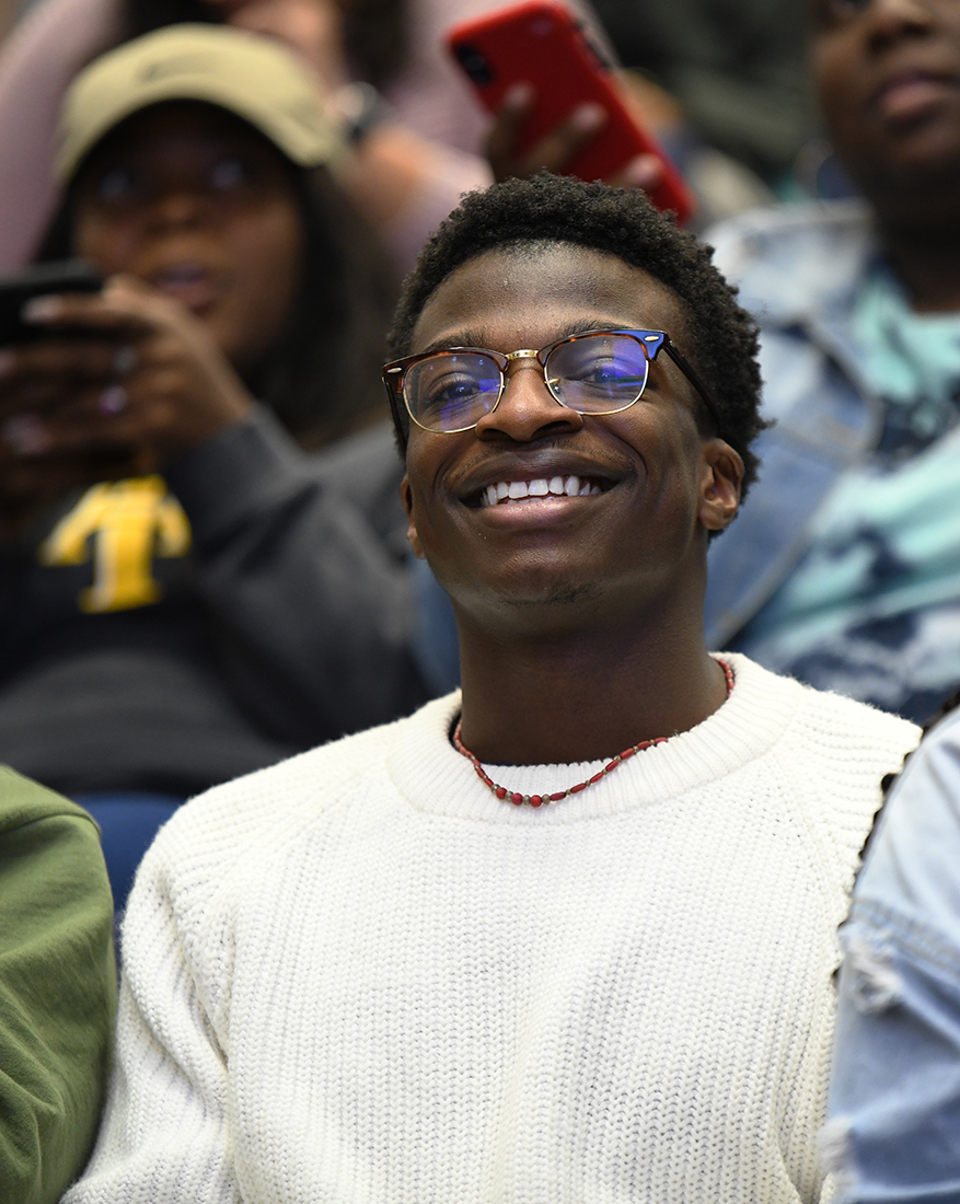 A student smiles in the audience during the engineers week kickoff ceremony