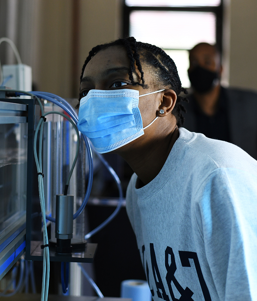 Mechanical engineer Chelsea Wilson makes observations at the wave tank. Her professor Michael Atkinson assists in the background.