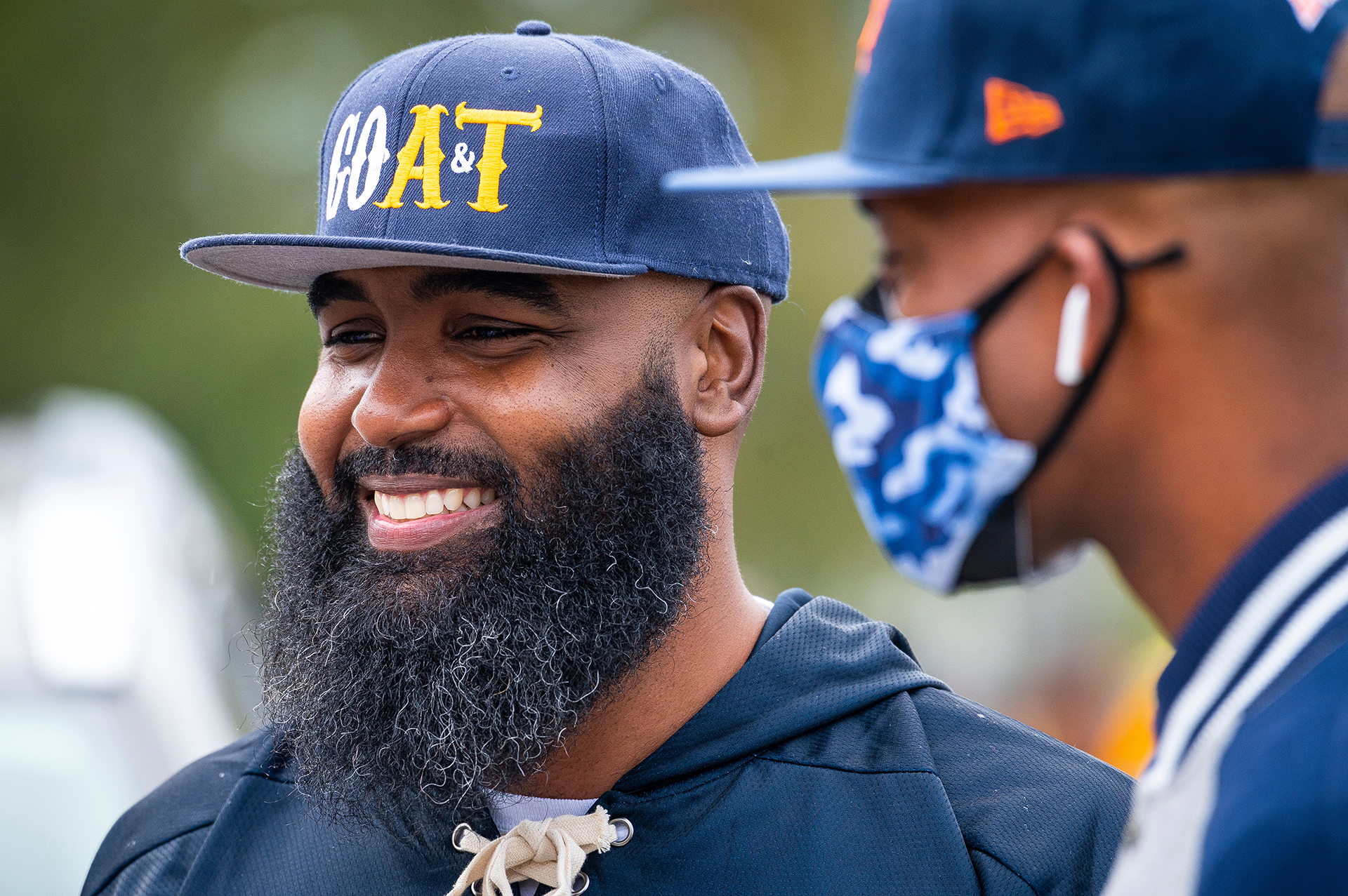 2 male alumni at N.C. A&T homecoming, one beared with a hat aond one masked