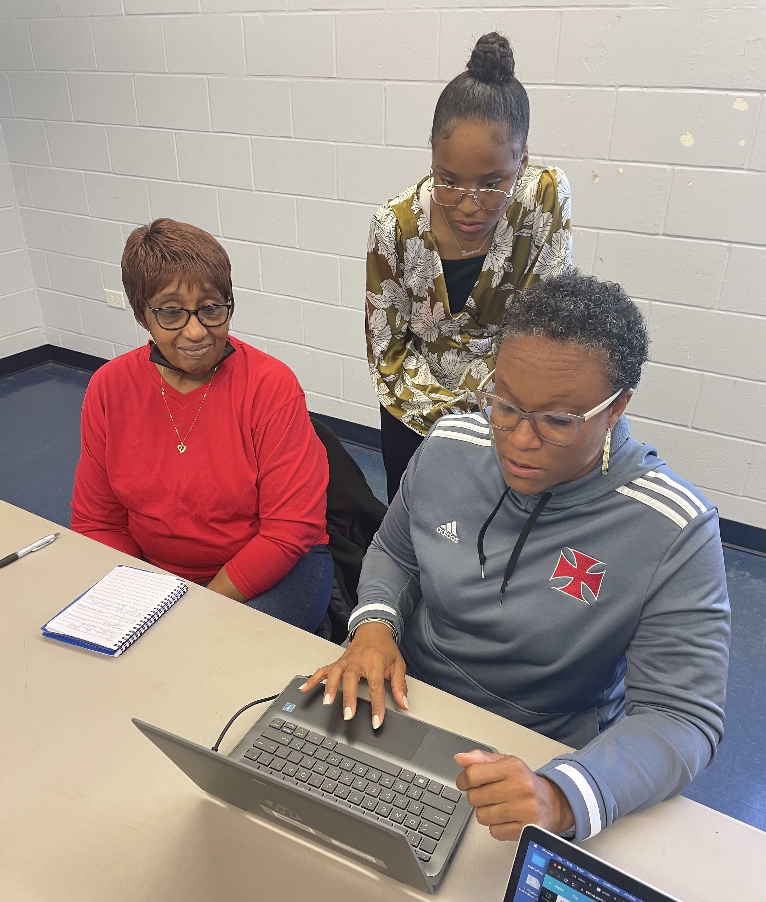 Zamaria Kinsey stands to help two women at a computer