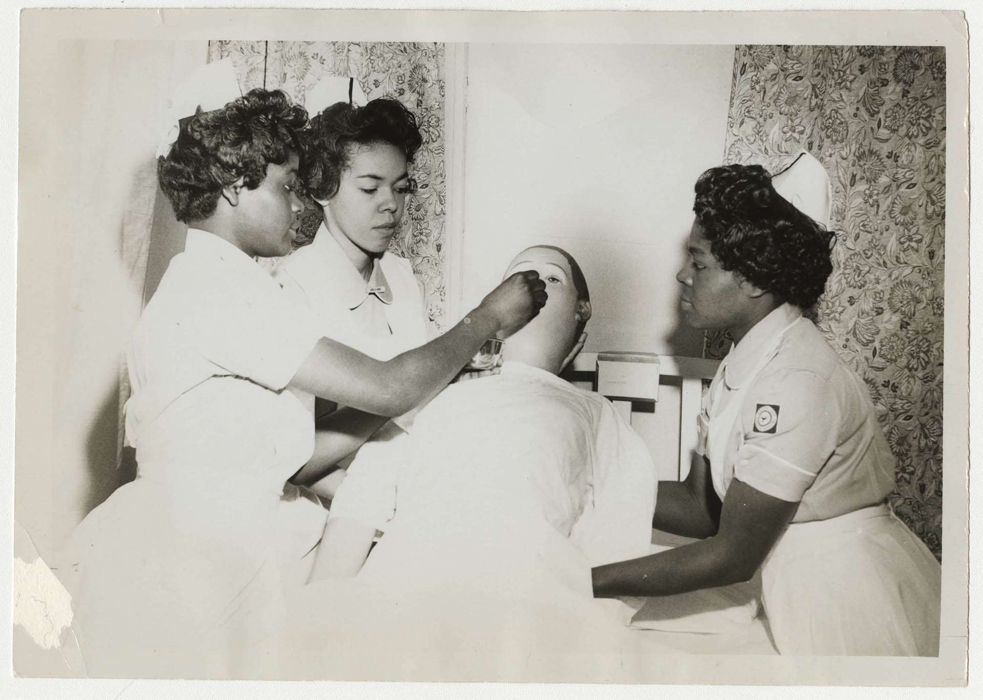 Three of the first School of Nursing students practice on a mannequin