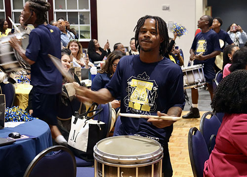 A Cold Steel drummer smiles while performing for a crowd in the Alumni-Foundation Event Center ballroom